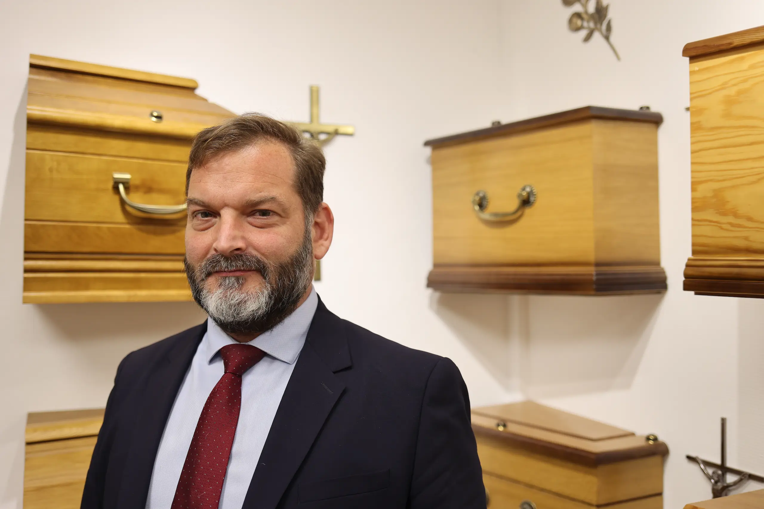Portrait d'Olivier Bousquet des Services Funéraires de l'Espérance devant des modèles de cercueils.