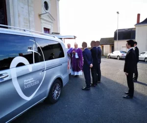 Corbillard des pompes funèbres garé devant une église pour une cérémonie d'obsèques.